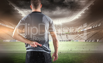 Composite image of rear view of rugby player with fingers crosse