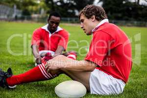 Rugby players sitting on grass before match