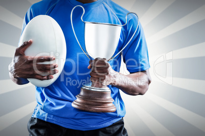 Composite image of mid section of sportsman holding trophy and r