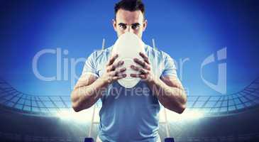 Composite image of rugby player looking at camera with ball