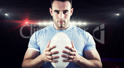 Composite image of rugby player looking at camera with ball