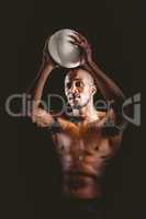 Shirtless athlete throwing rugby ball