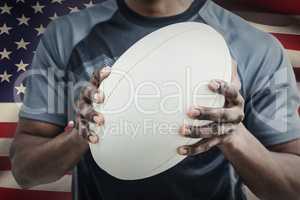 Composite image of mid section of sportsman holding rugby ball