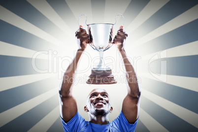 Composite image of happy sportsman looking up while holding trop