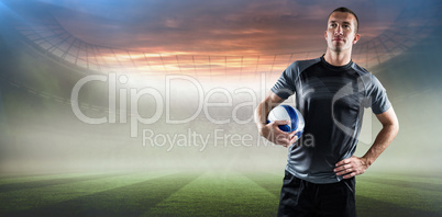 Composite image of rugby player holding ball with hand on hip