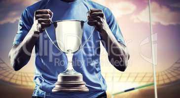 Composite image of mid section of sportsman holding trophy