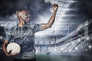 Composite image of sportsman with clenched fist holding rugby ba