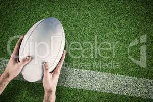 Composite image of a rugby player posing a rugby ball