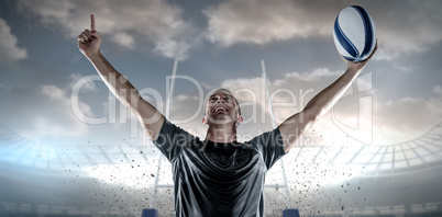 Composite image of successful rugby player holding ball with arms raised