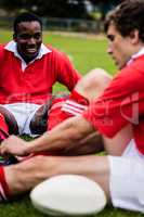 Rugby players sitting on grass before match