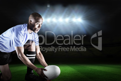 Composite image of rugby player looking away while keeping ball