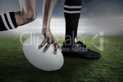 Composite image of low section of athlete holding ball while running