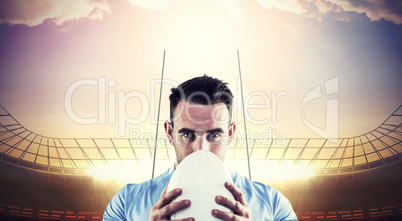 Composite image of rugby player looking at camera with ball