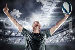 Composite image of successful rugby player holding ball with arm