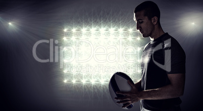 Composite image of calm rugby player thinking while holding ball