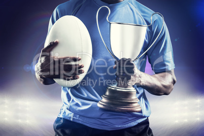 Composite image of mid section of sportsman holding trophy and r Composite image of mid section of sportsman holding trophy and r
