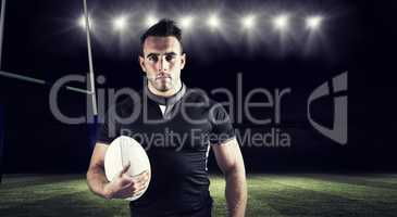 Composite image of tough rugby player holding ball