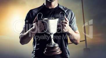 Composite image of victorious rugby player holding trophy