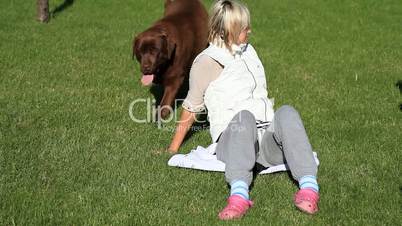 Little girl and her mom playing with a Brown Labrador retriever in spring