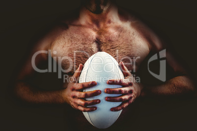 Shirtless rugby player holding ball