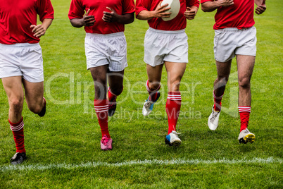 Rugby players jogging with ball