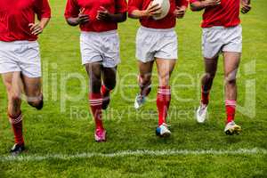 Rugby players jogging with ball