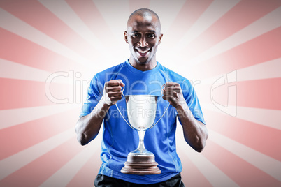 Composite image of portrait of happy sportsman holding trophy