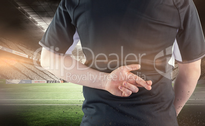 Composite image of back turned rugby player with fingers crossed