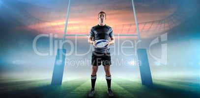 Composite image of serious rugby player in black jersey holding ball