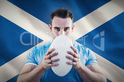 Composite image of rugby player looking at camera with ball