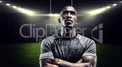 Composite image of thoughtful rugby player with arms crossed