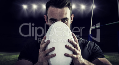 Composite image of tough rugby player holding ball