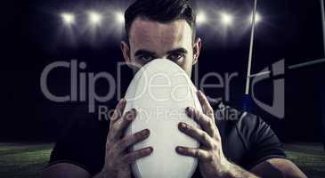 Composite image of tough rugby player holding ball