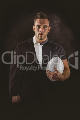 Composite image of tough rugby player holding ball