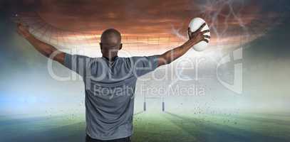 Composite image of rear view of sportsman with arms raised holding rugby ball