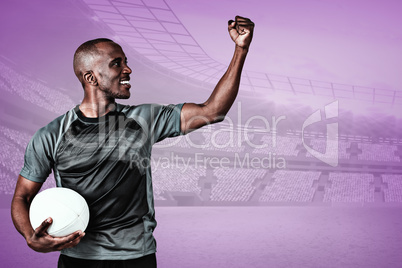 Composite image of sportsman with clenched fist holding rugby ba