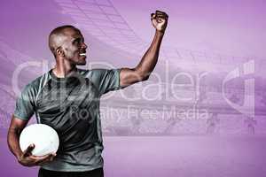 Composite image of sportsman with clenched fist holding rugby ba