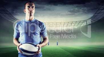 Composite image of confident rugby player holding ball