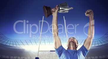 Composite image of happy rugby player holding trophy