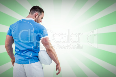 Composite image of rugby player standing with ball