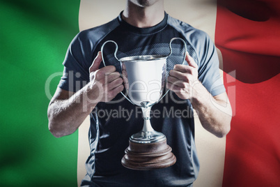 Composite image of victorious rugby player holding trophy