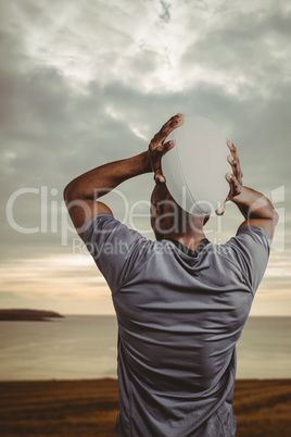 Composite image of rear view of sportsman throwing rugby ball