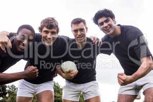 Rugby players cheering together with ball