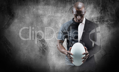 Composite image of thoughtful athlete looking at rugby ball