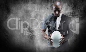 Composite image of thoughtful athlete looking at rugby ball