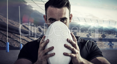 Composite image of tough rugby player holding ball