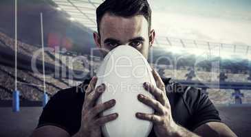 Composite image of tough rugby player holding ball