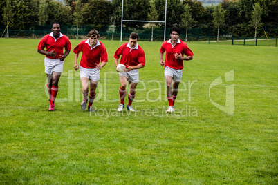 Rugby players jogging with ball