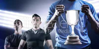 Composite image of mid section of sportsman holding trophy