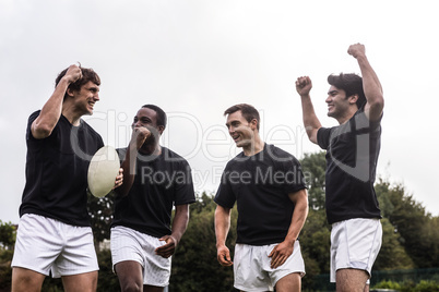 Rugby players cheering together with ball